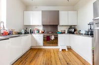 a kitchen with wooden floors and white cabinets