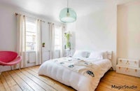 a white bedroom with wooden floors and a pink chair